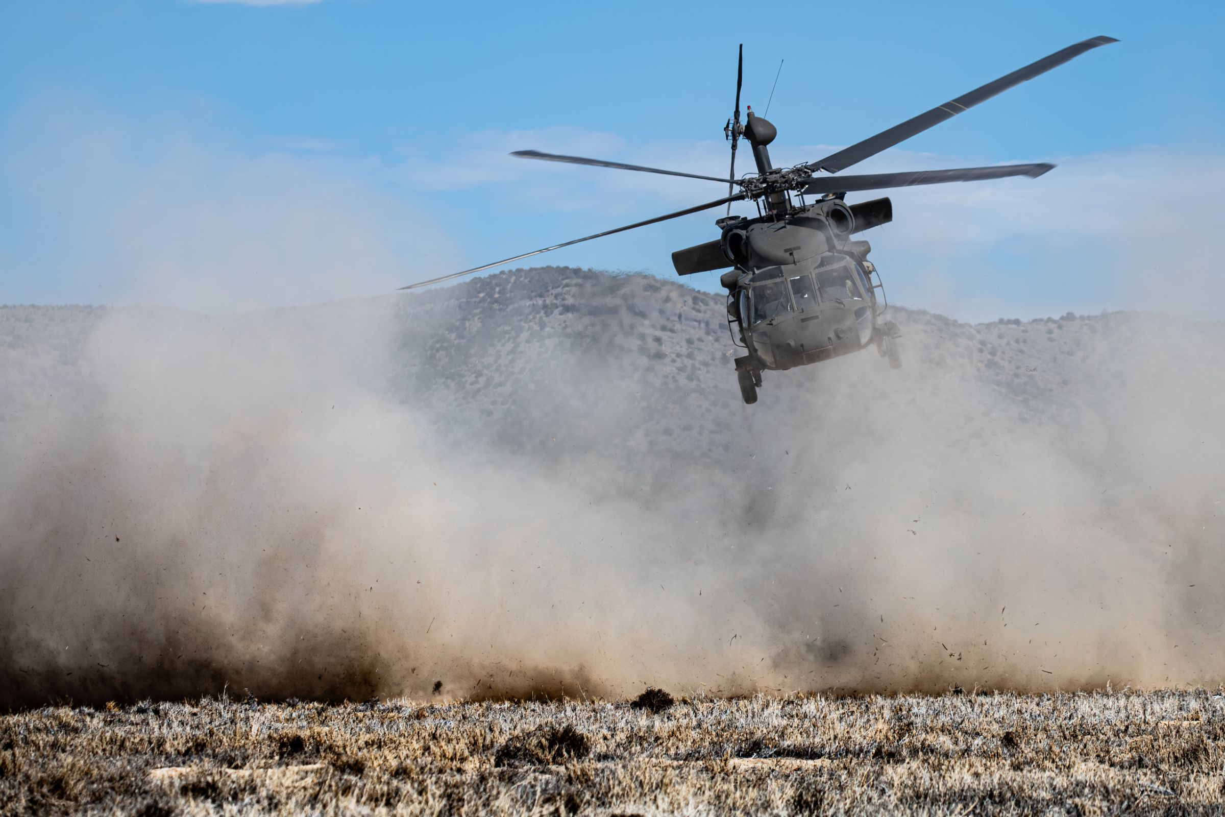 Army Black Hawk helicopter landing in a cloud of dust